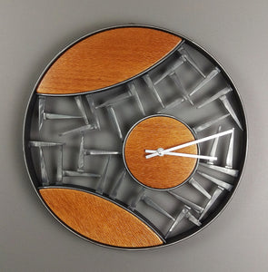 Wall clock with round black metal frame, inside cat eye segments are orange wood surrounded by cut steel nails