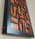 Wood and Metal wall art, black steel frame with pattern of nails across orange red wood surface, copper details along edge of steel frame