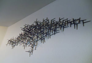 Wide black metal wall sculpture, made from welded nails, overall scion shape