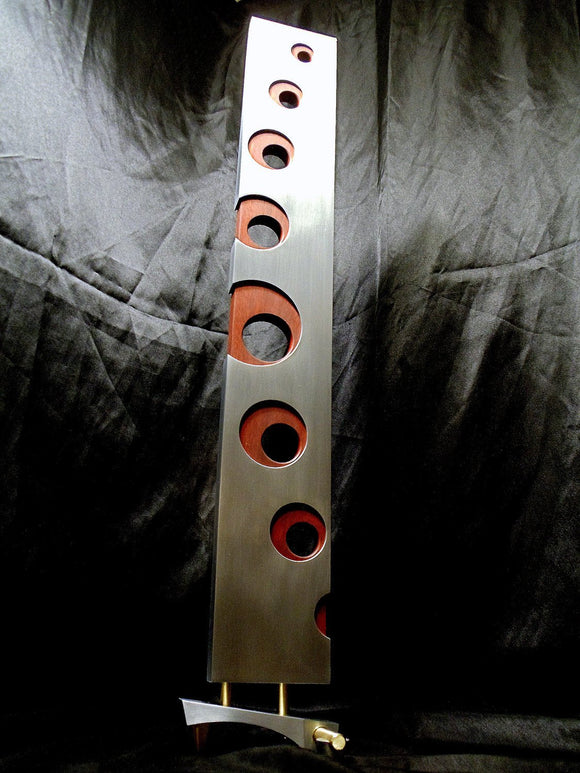 tall narrow silver metal sculpture with arced hole pattern, red wood inlays, and silver and brass base